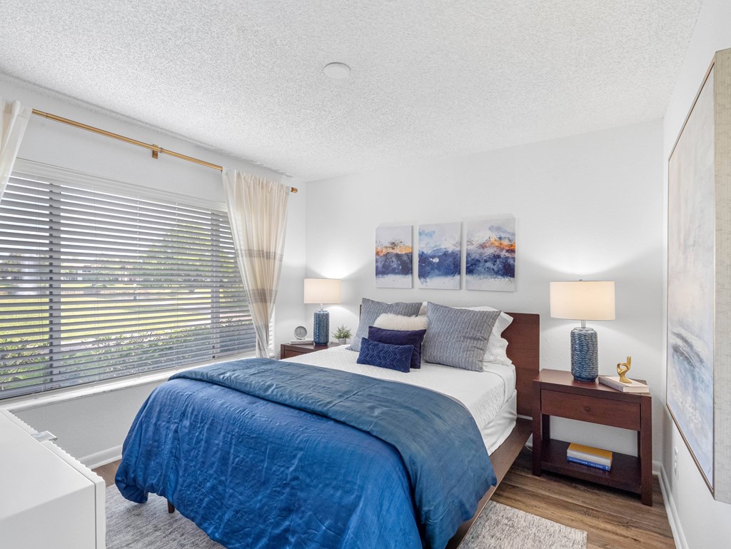A bedroom with a bed, nightstands, and pictures on the wall.